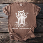 Brown t-shirt with distressed graphic of a shouting raccoon and text "become ungovernable".