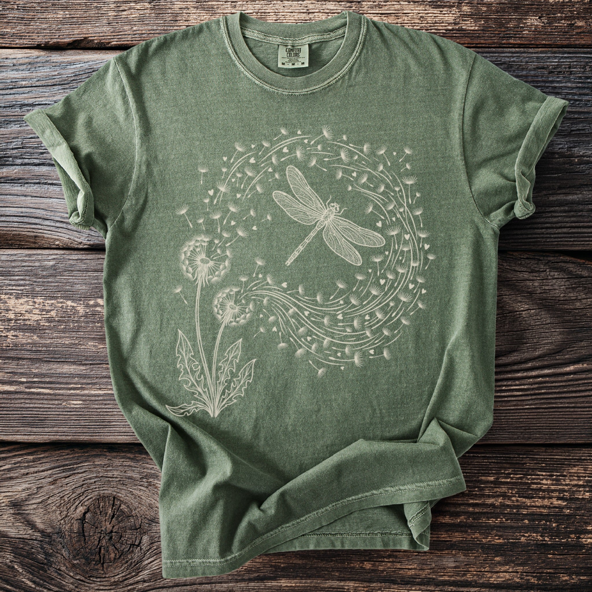 Green t-shirt with a white line drawing of a dragonfly and dandelions.