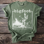 Green t-shirt with Bigfoot sitting by a campfire and the text "bigfoot grabbed my weiner".