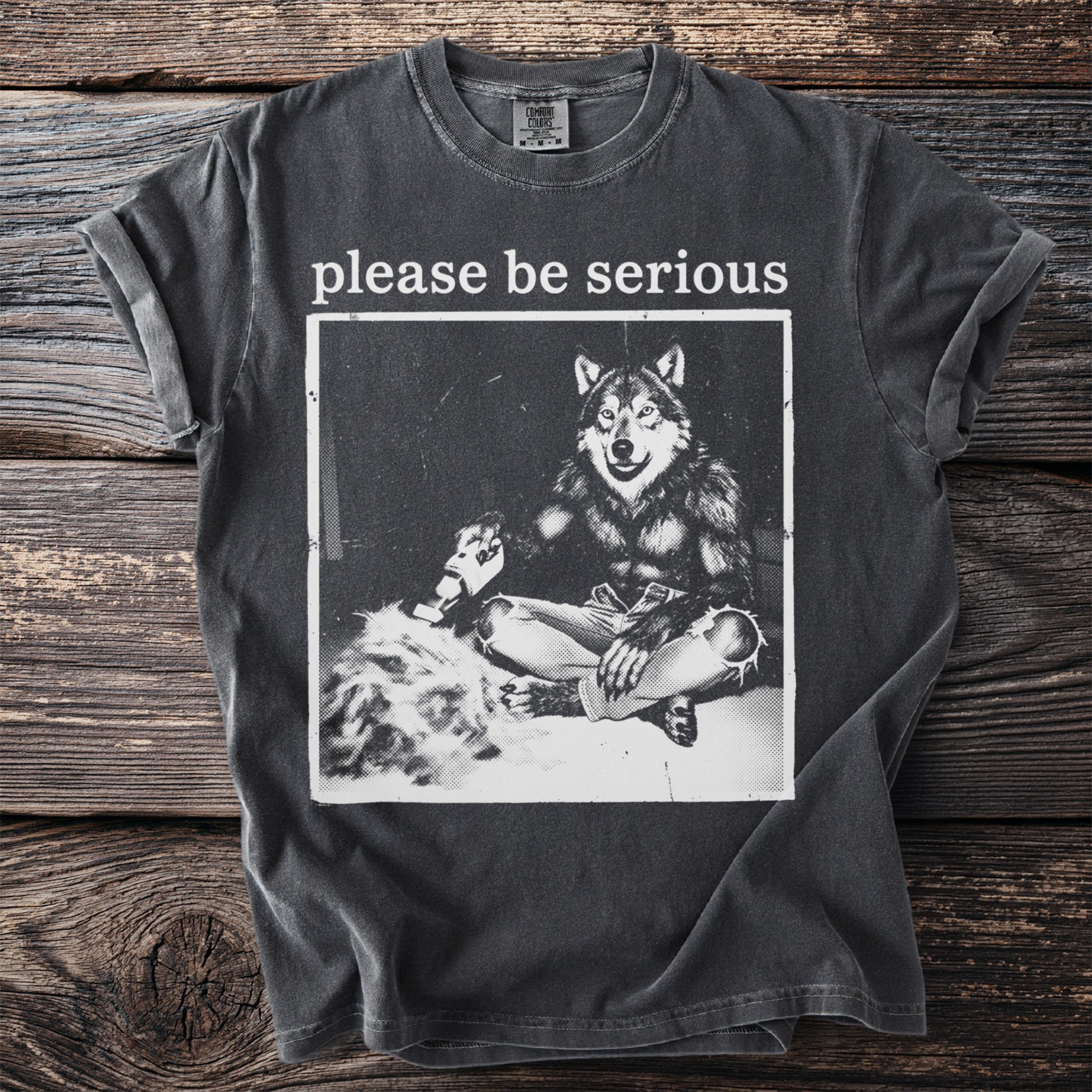 Dark grey t-shirt with "please be serious" text above a werewolf graphic.