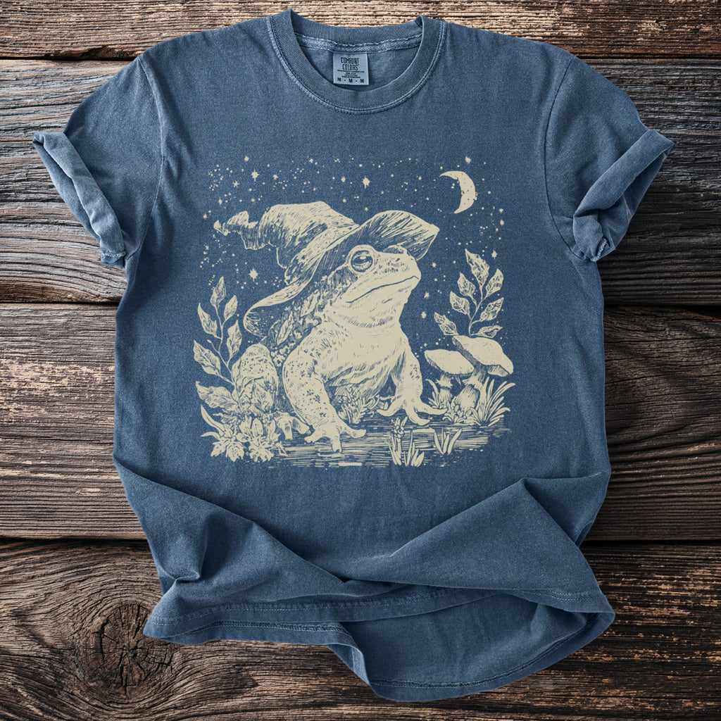 Blue t-shirt with a cream line art print of a frog wearing a wizard hat.