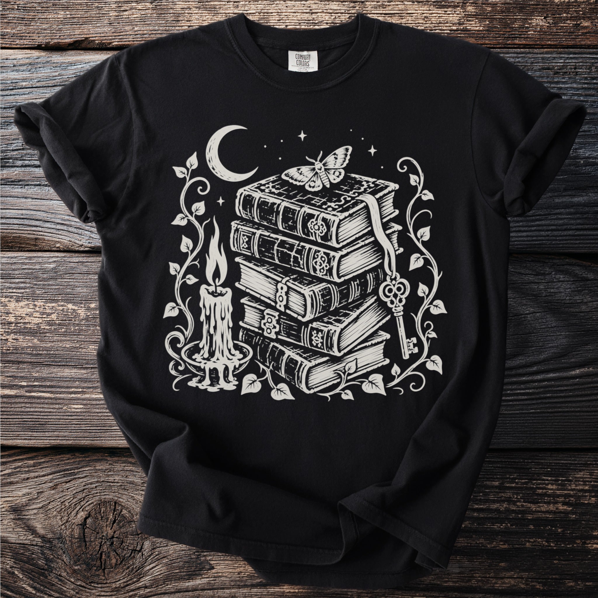 Black t-shirt with stylized stack of books, candle, key, moon, and moth graphic.