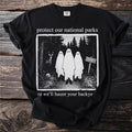 Black t-shirt with "protect our national parks or we'll haunt your backy" text and ghost graphic.
