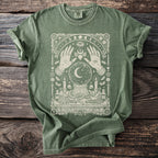 Green t-shirt with arcane illustration of hands, crystal ball, snake, and candles.