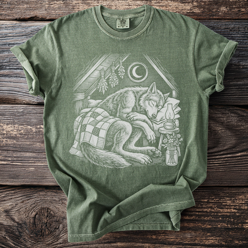 Green t-shirt with a drawing of a sleeping wolf under a crescent moon and star.