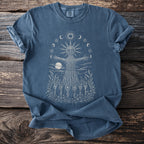 Blue t-shirt with a woven figure, sun, moons, and figures in a field.