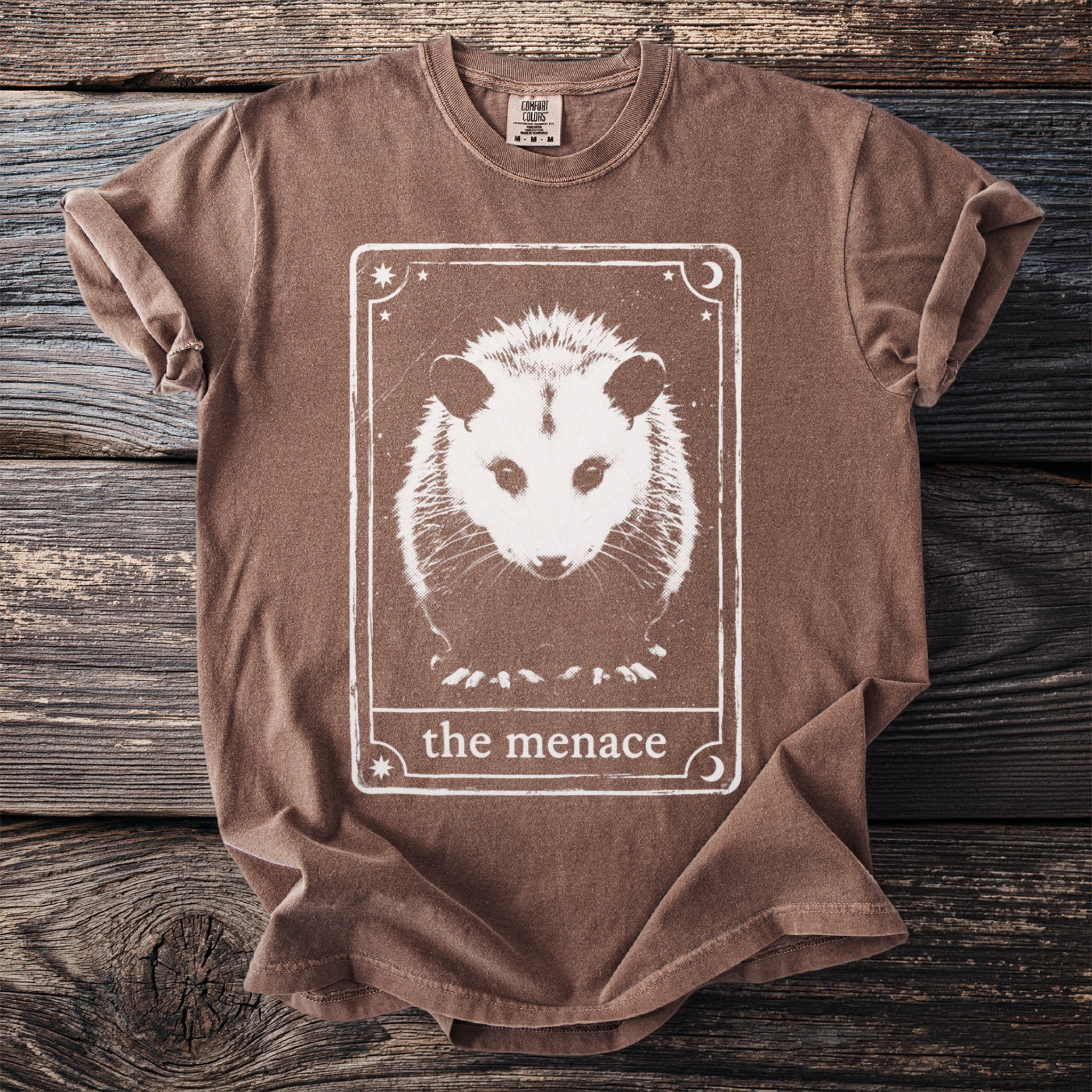 Brown t-shirt with white opossum tarot card graphic and text "the menace".