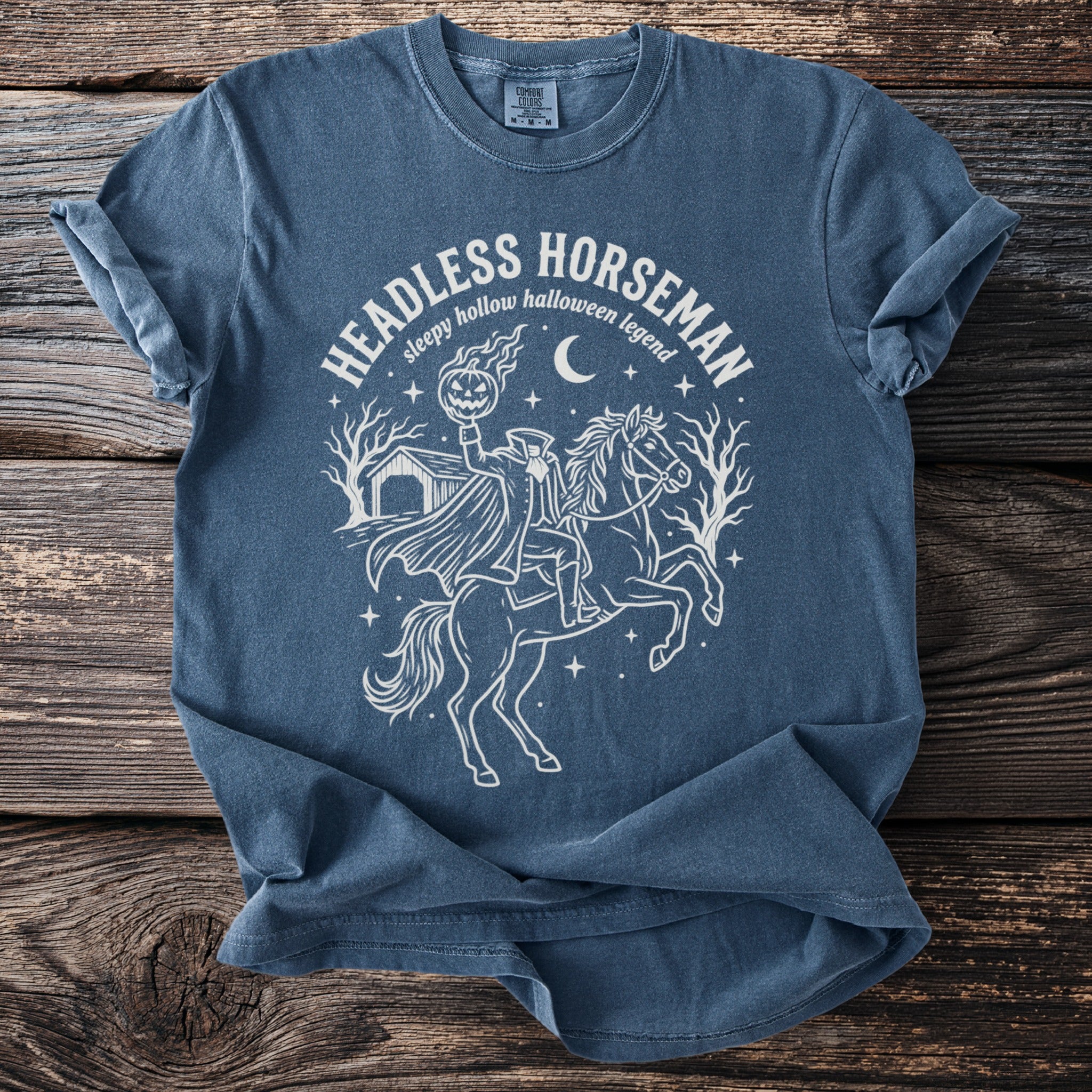 T-shirt with a white line drawing of the Headless Horseman holding a pumpkin and riding a horse.