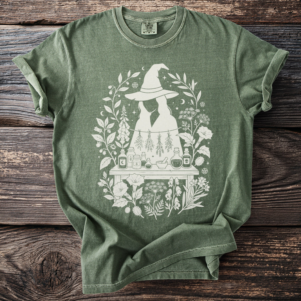 Green t-shirt with white mystical botanical and witchy illustration.