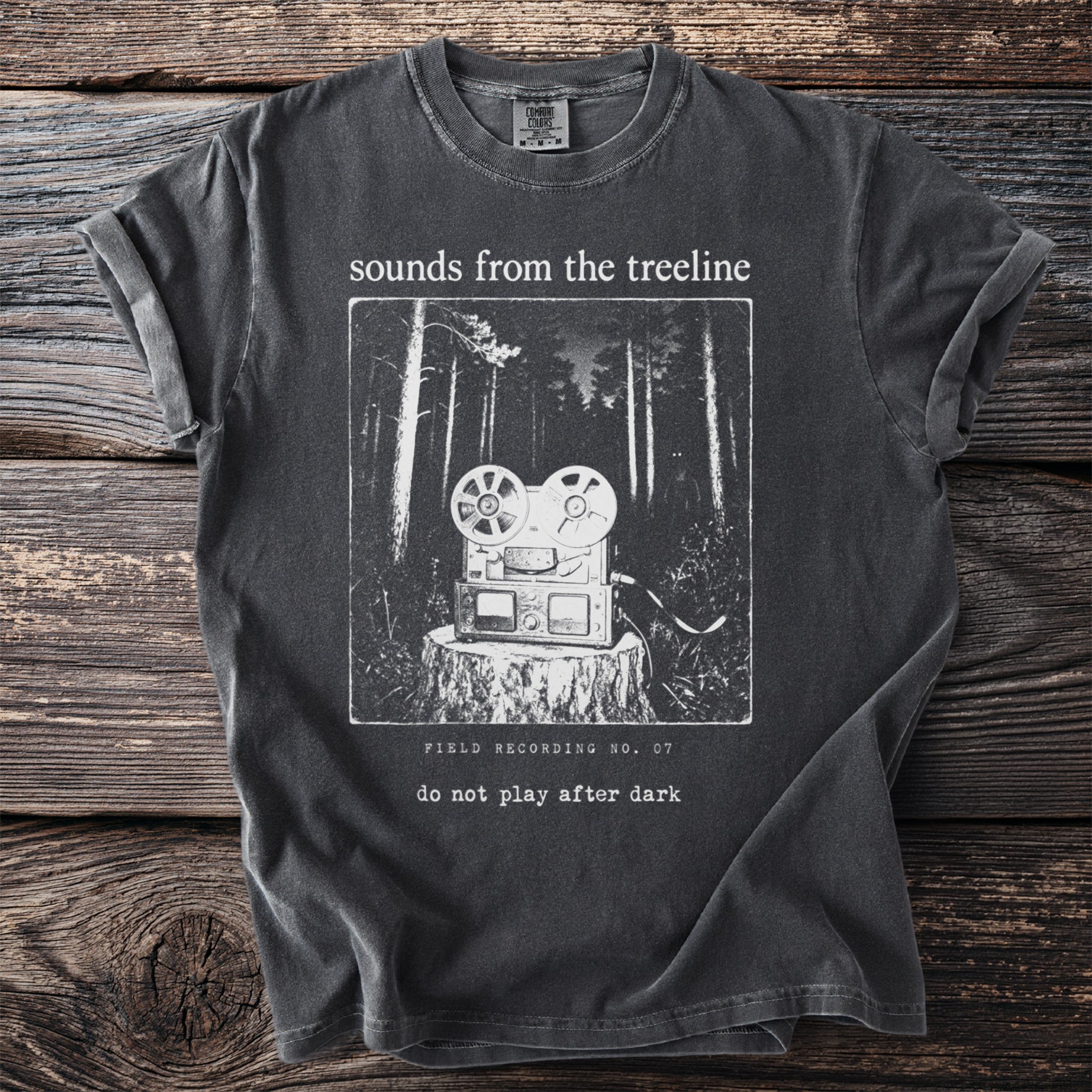 Dark grey t-shirt with a graphic of a reel-to-reel tape recorder on a tree stump in a forest.