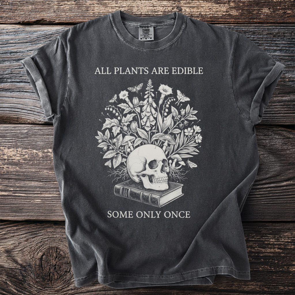 Dark t-shirt with skull, plants, and text "ALL PLANTS ARE EDIBLE SOME ONLY ONCE".