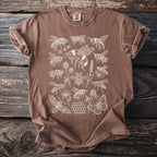 Brown t-shirt with a white line-art design of various bees, butterflies, flowers, and a honeycomb.