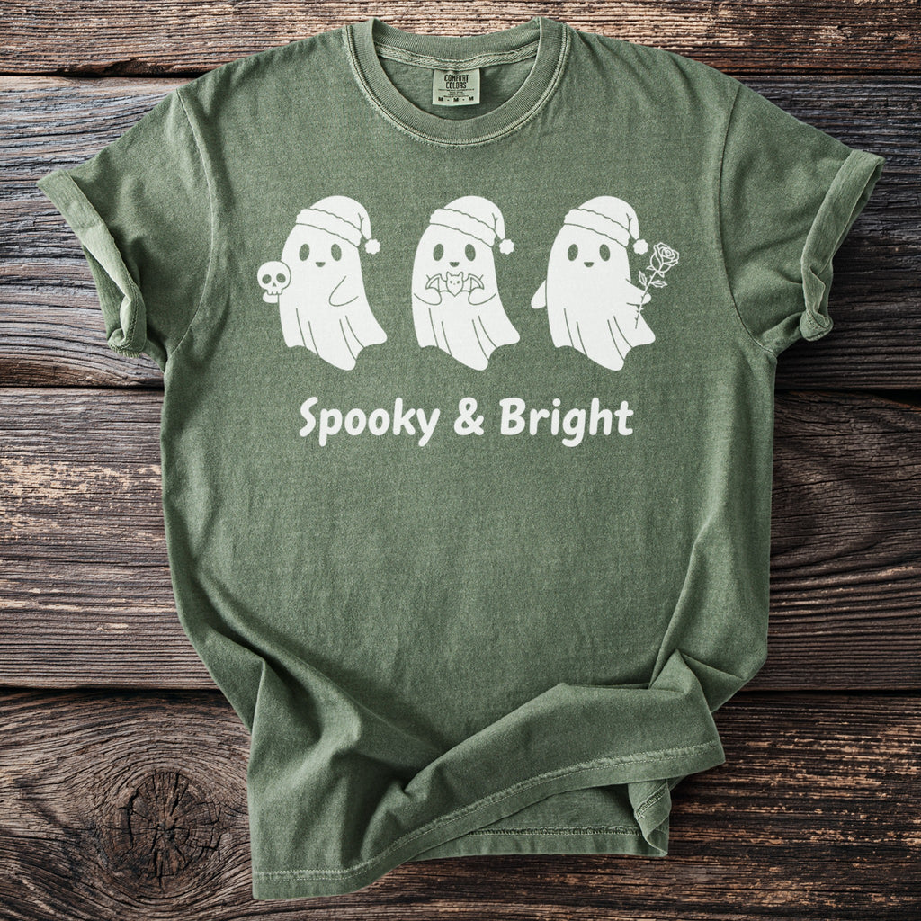 Green t-shirt with three white ghosts wearing Santa hats and text "Spooky & Bright".