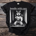 Black t-shirt with "handle with care" and wolf holding a kitten graphic.