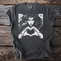 The Morrigan Heart Hands design on a pepper grey t-shirt: a feather-haired woman forming a heart with her hands, a raven perched on her wrist.