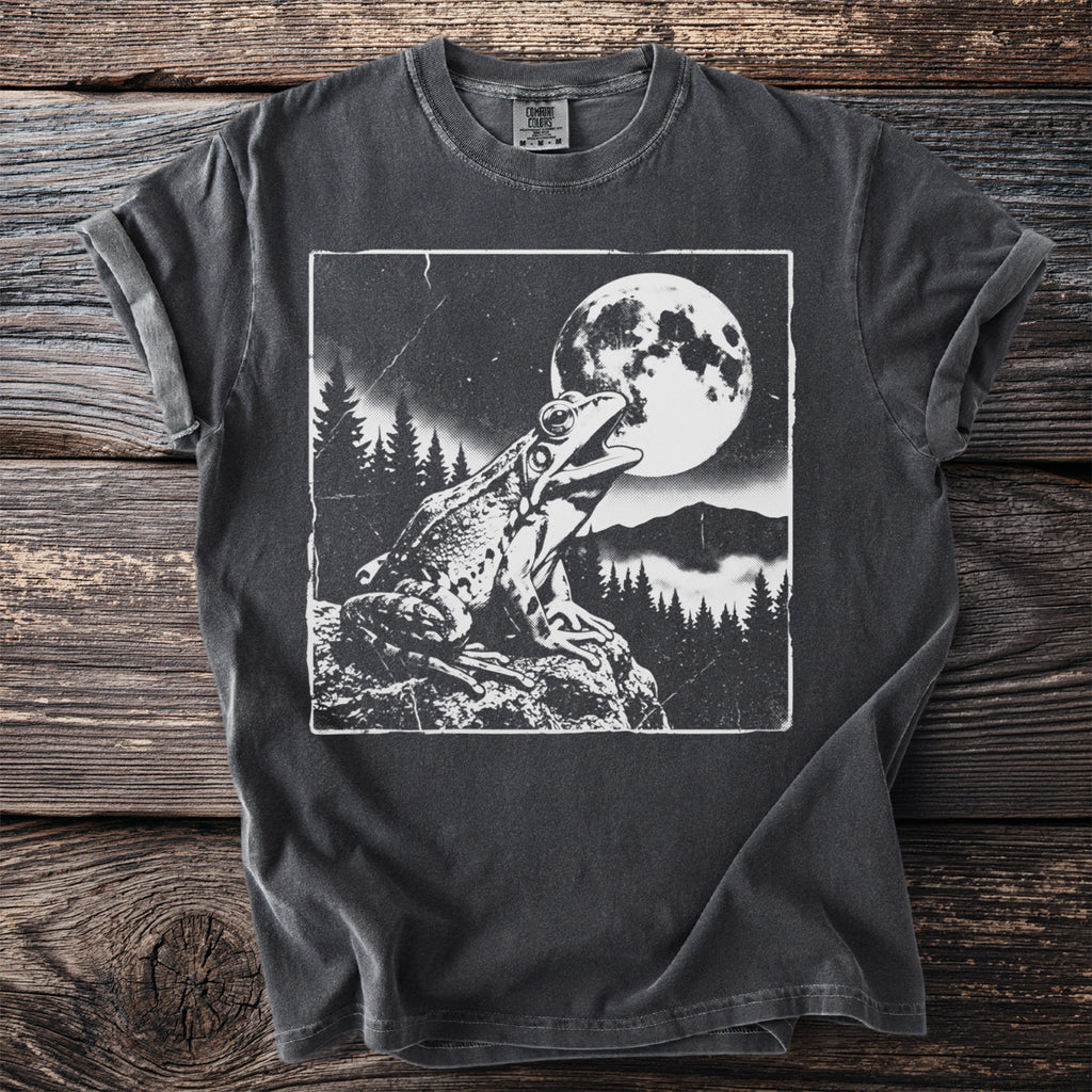 Black t-shirt with a graphic of a frog by a full moon in a forest.