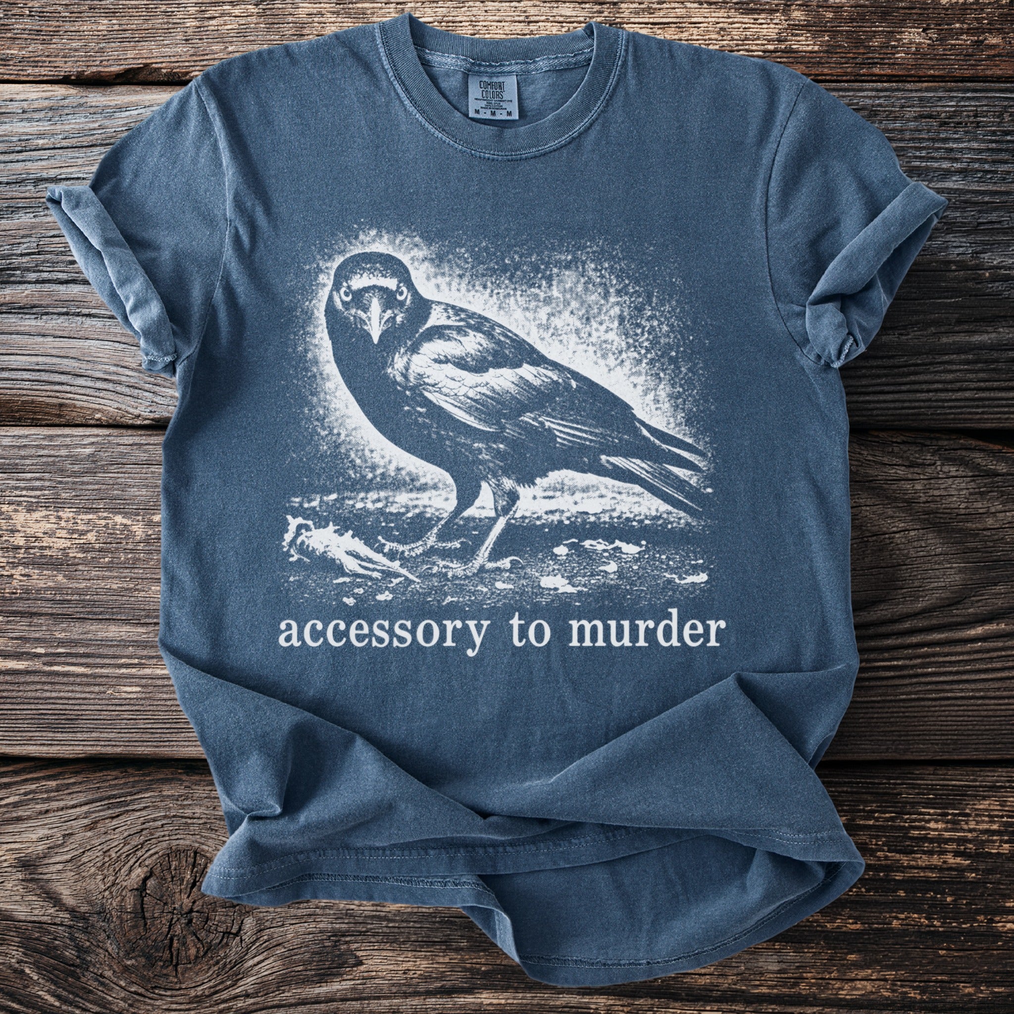 Blue t-shirt with white crow graphic and text Accessory to Murder