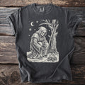 Pepper gray t-shirt with a cream folk-cut print: the Reaper crouches over a small fire in the snow, roasting chestnuts in a long pan.