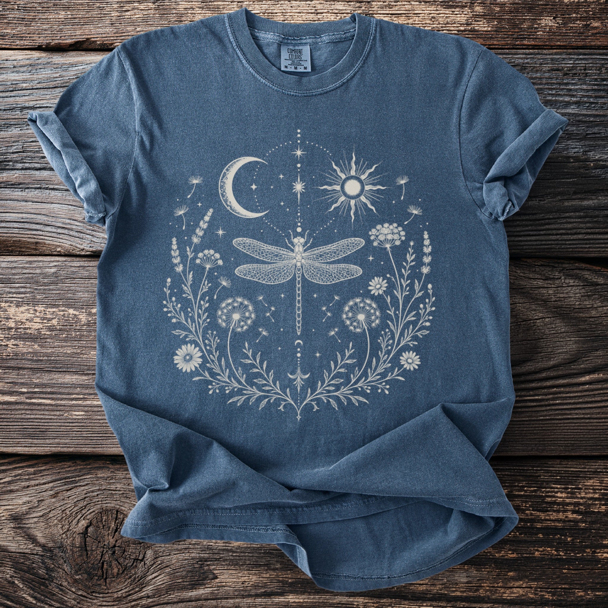 Blue t-shirt with a moon, sun, and dragonfly floral graphic.