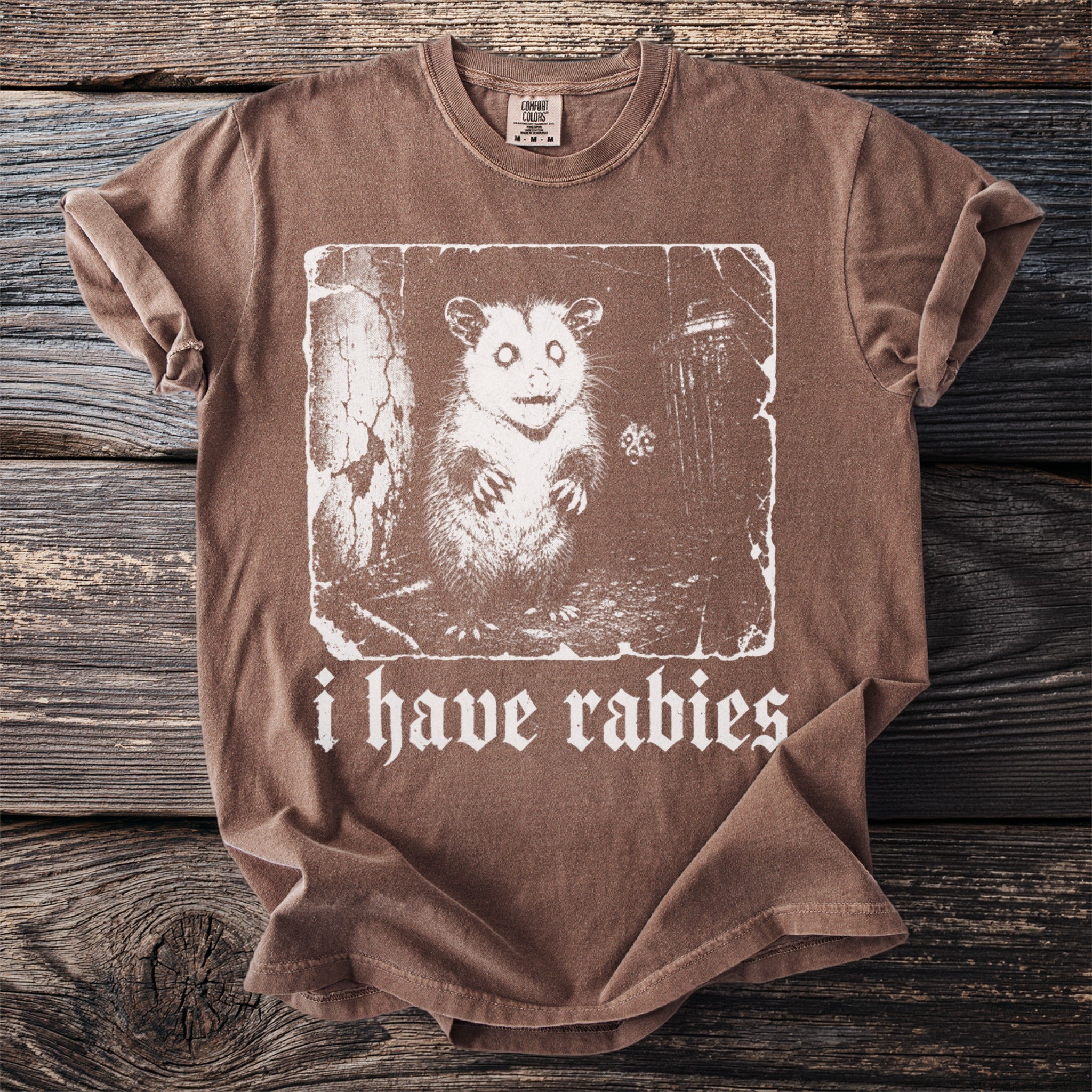 Brown t-shirt with a distressed graphic of an opossum and text reading "i have rabies".