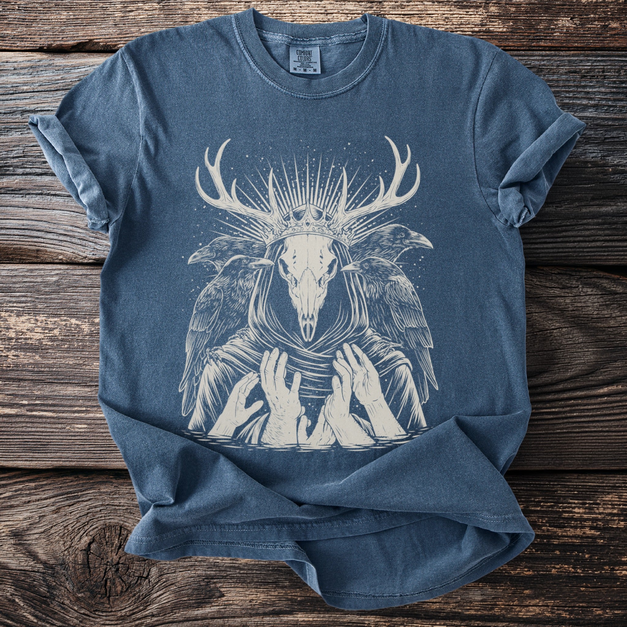 Blue t-shirt with a cream skull, antlers, crown, and ravens design.