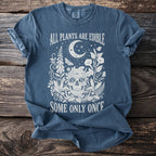 Blue t-shirt with a skull, crescent moon, plants, and text "ALL PLANTS ARE EDIBLE SOME ONLY ONCE".