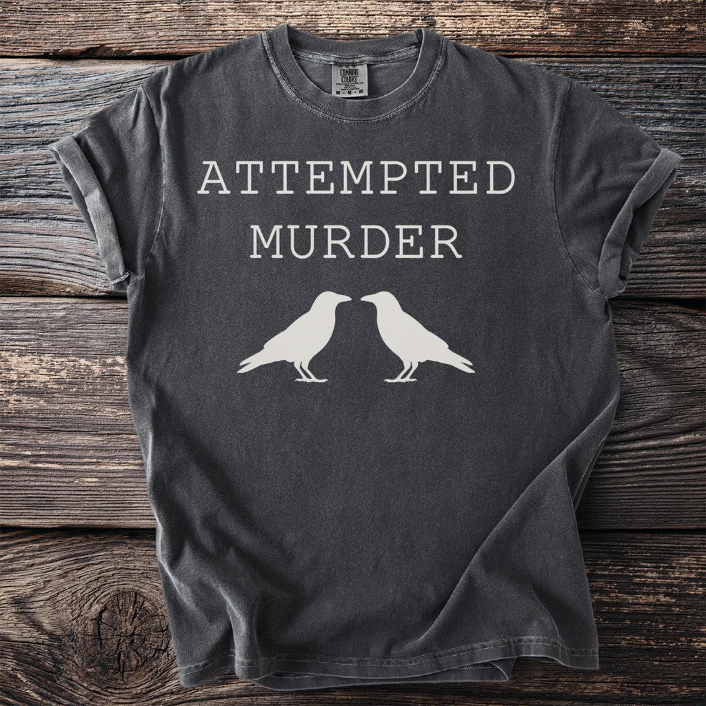 Dark grey t-shirt with white text "ATTEMPTED MURDER" and two crows.