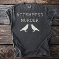 Dark grey t-shirt with white text "ATTEMPTED MURDER" and two crows.