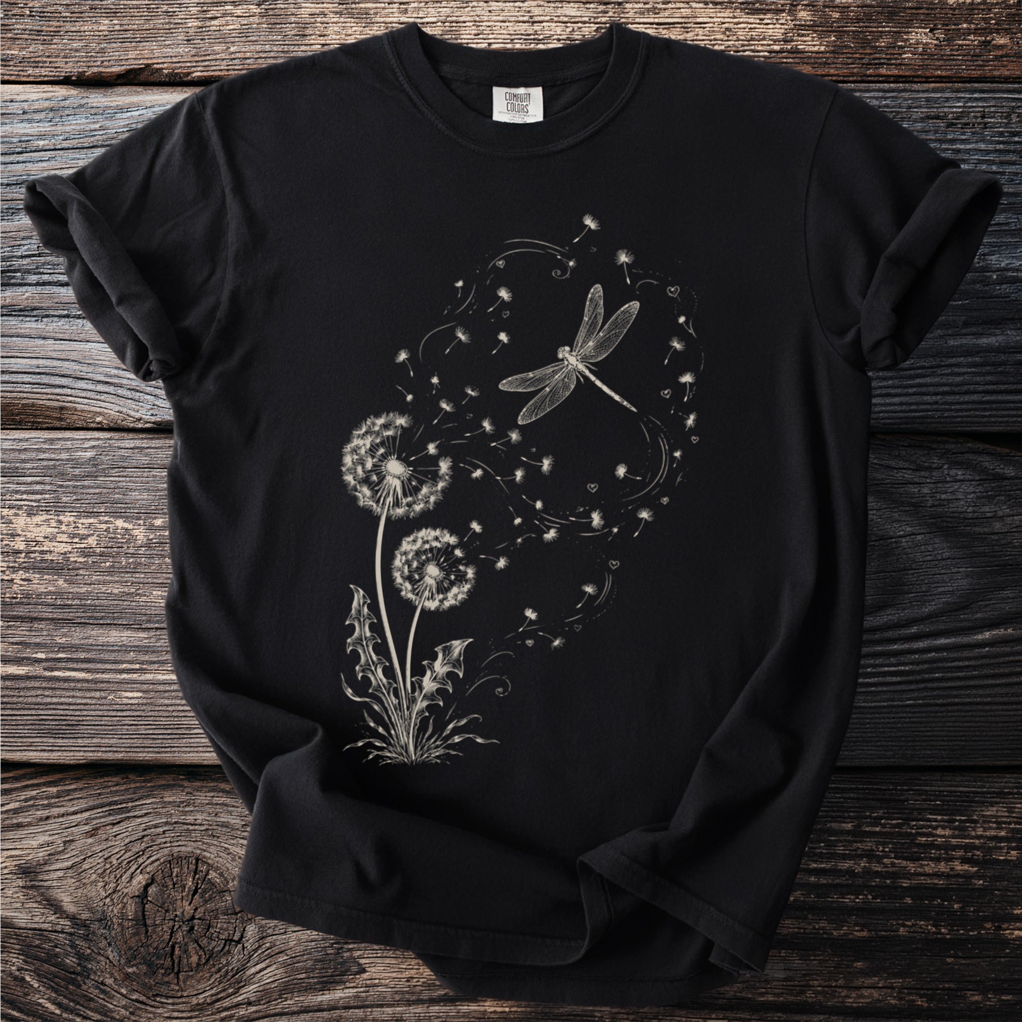 Black t-shirt with a cream-colored line drawing of dandelions and a dragonfly.