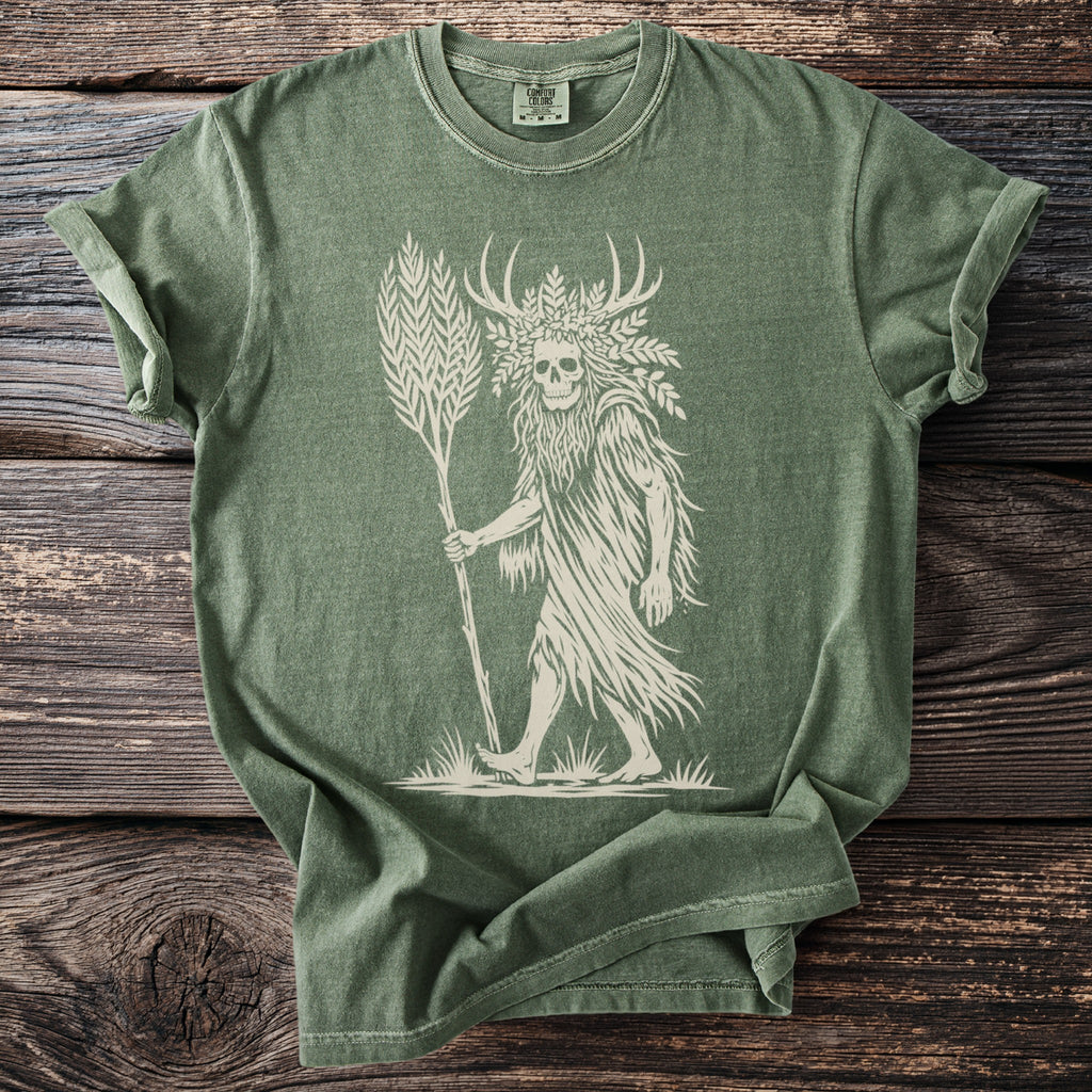 Green t-shirt with a cream graphic of a skull-headed figure with antlers and a staff.