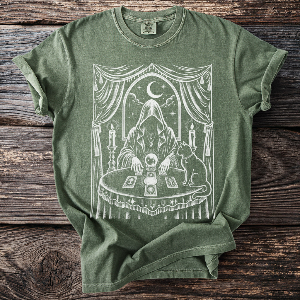Green t-shirt with white occult design of figure, crystal ball, tarot cards, and a cat.
