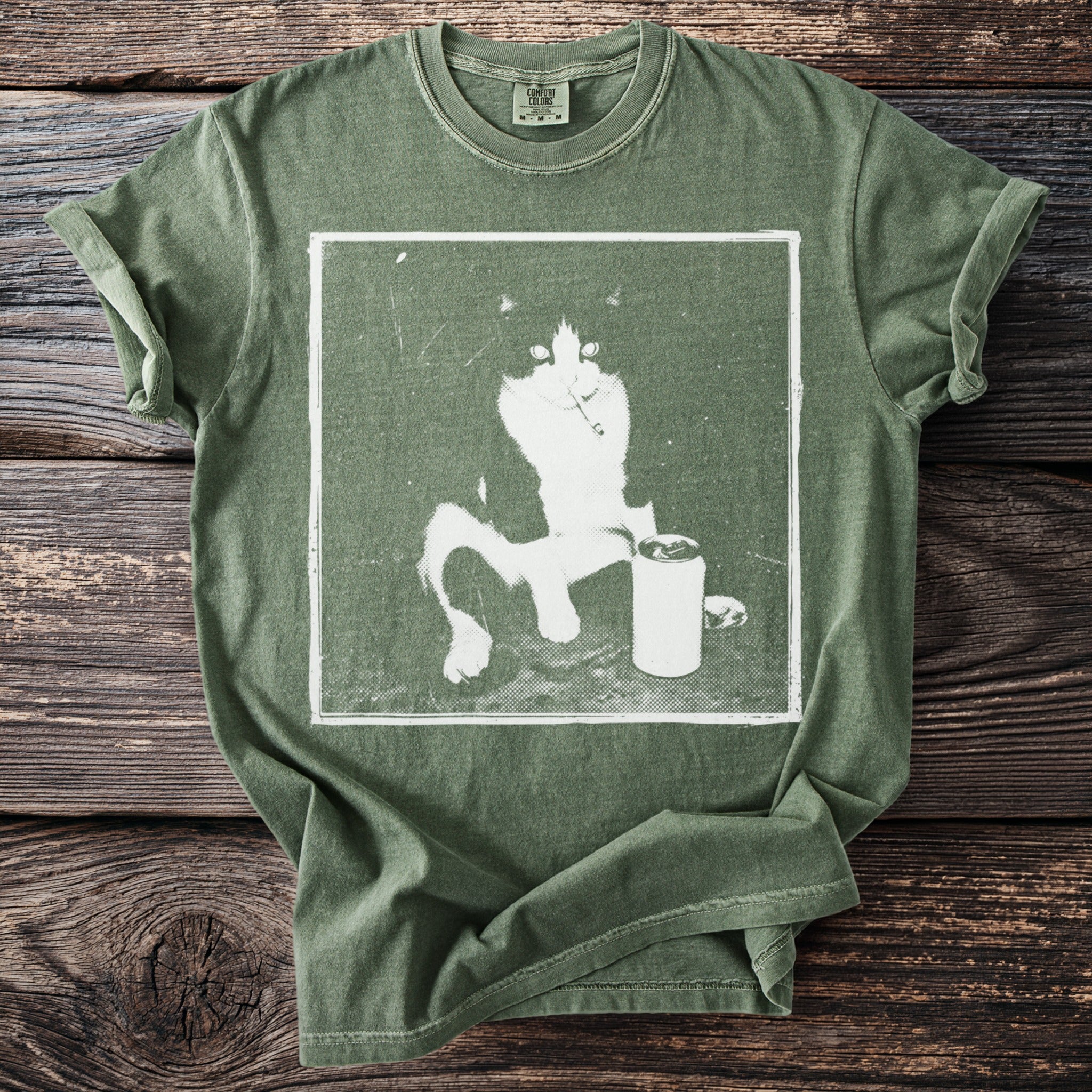 Green t-shirt with a distressed graphic of a black and white cat next to a can.