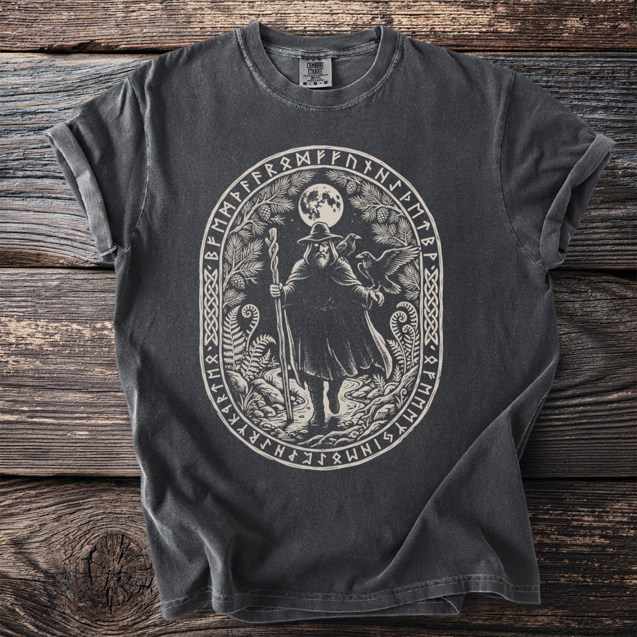 Dark t-shirt with an oval design of a bearded man with staff and ravens, surrounded by runes.