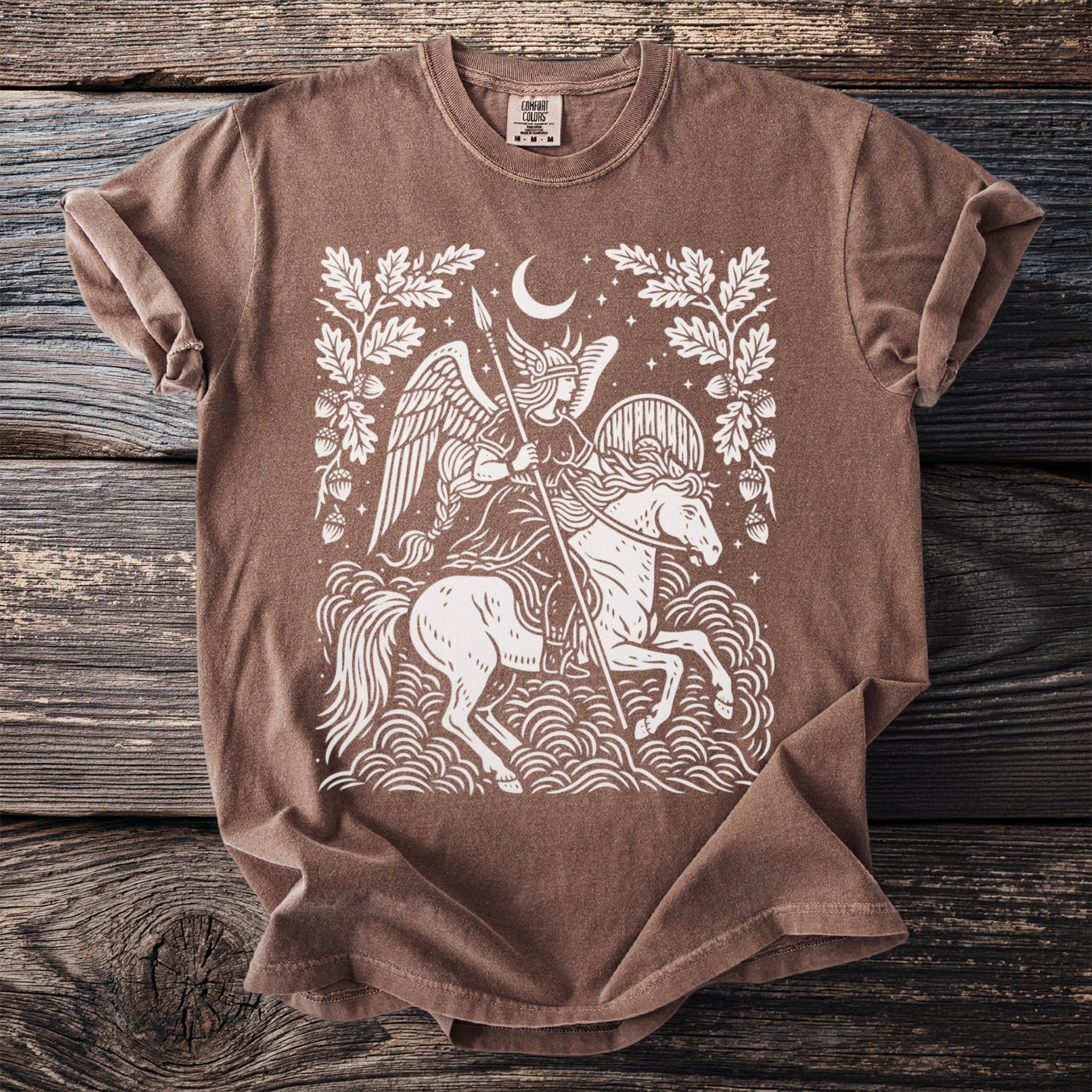 Brown t-shirt with graphic of winged woman on horse under moon surrounded by oak leaves.