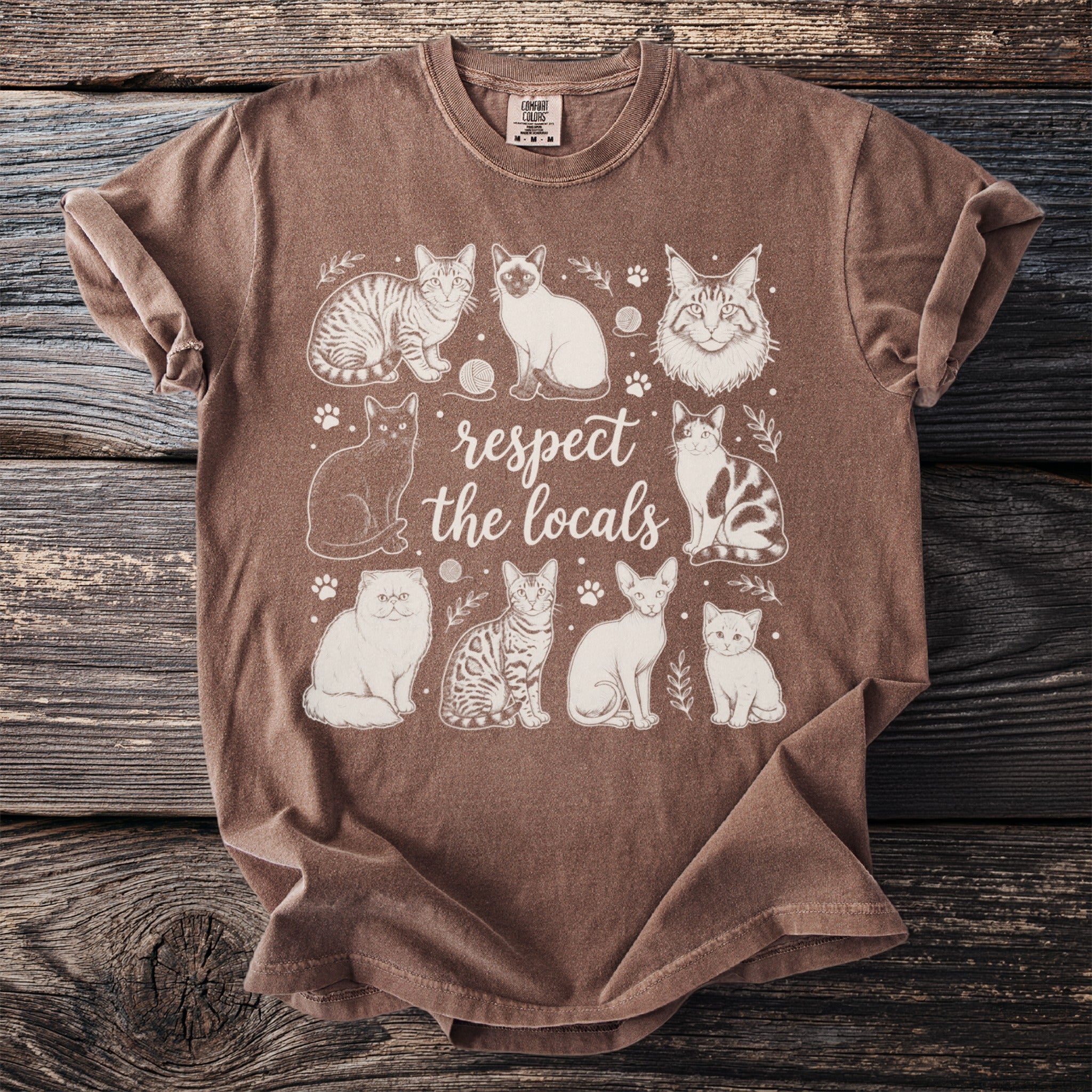 Brown t-shirt with graphic of various cats and text "respect the locals".