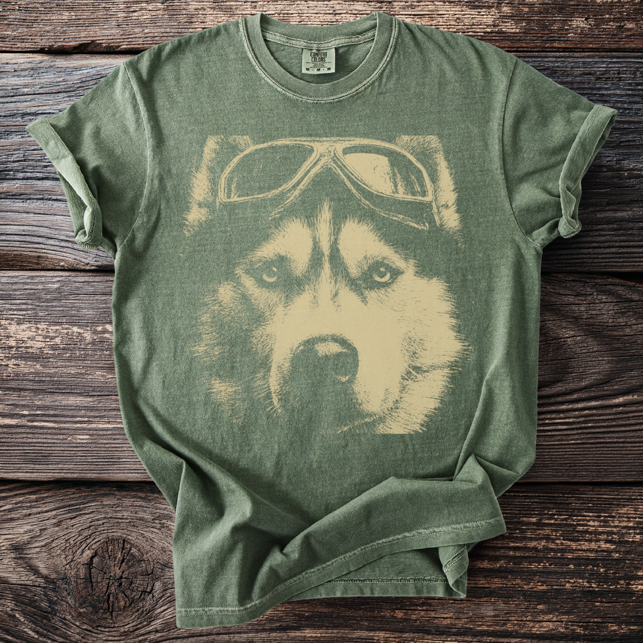 Green t-shirt with a tan graphic of a husky wearing aviator goggles.