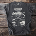 T-shirt with detailed opossum illustration, labeling its body parts and behaviors.