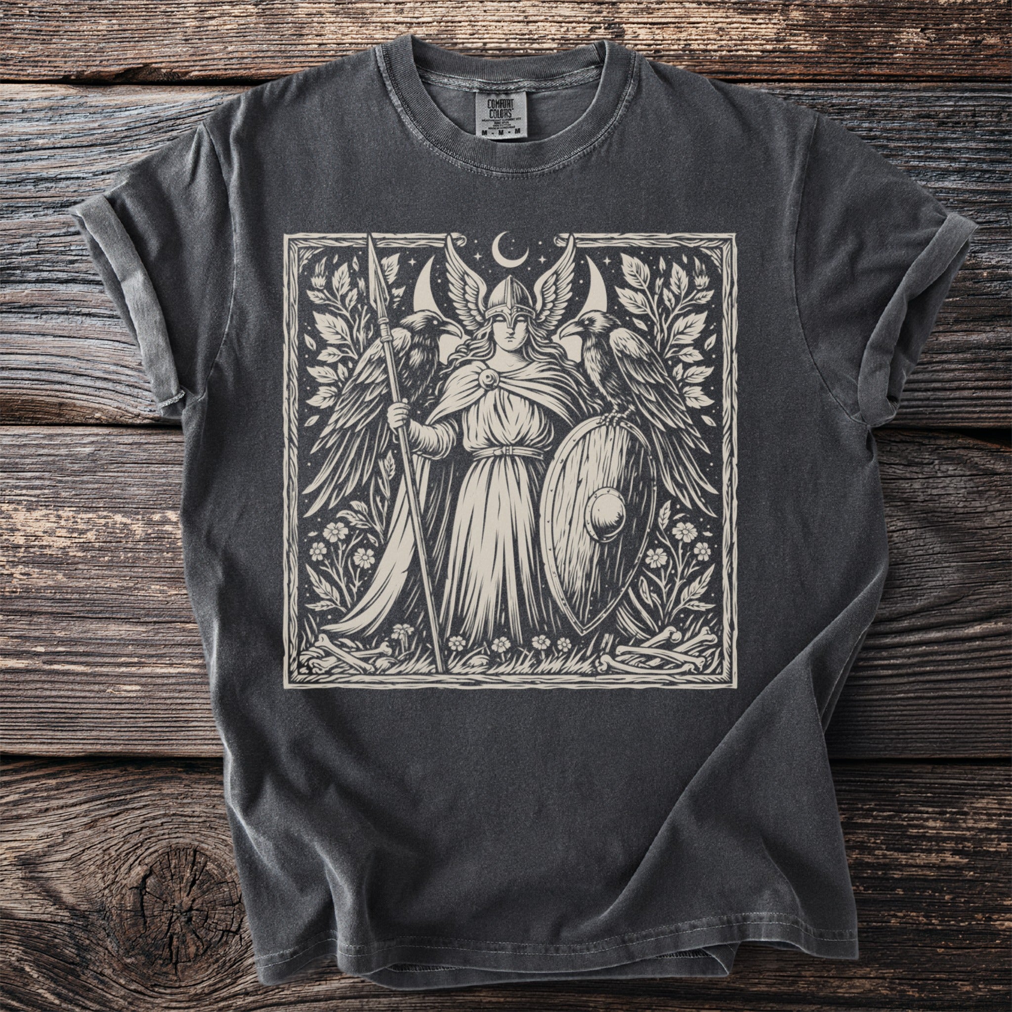 Valkyrie with shield and spear, flanked by ravens, beneath a crescent moon.