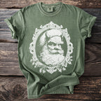 Green t-shirt with a white distressed graphic of a devilish Santa Claus in a frame.