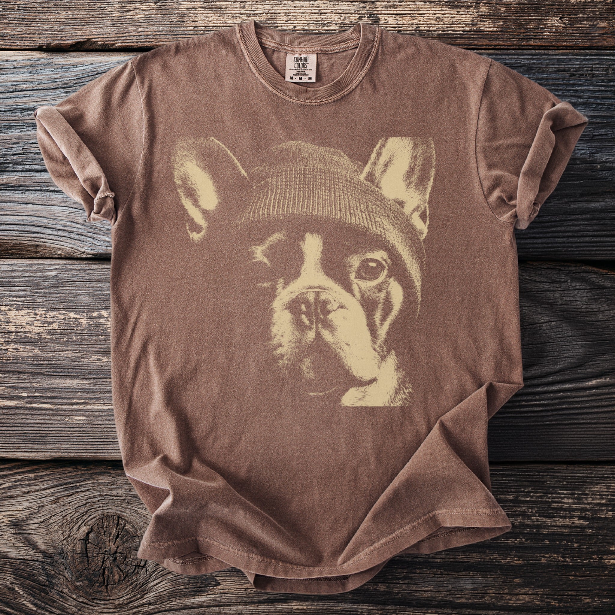 Brown t-shirt with a graphic of a French bulldog wearing a beanie.