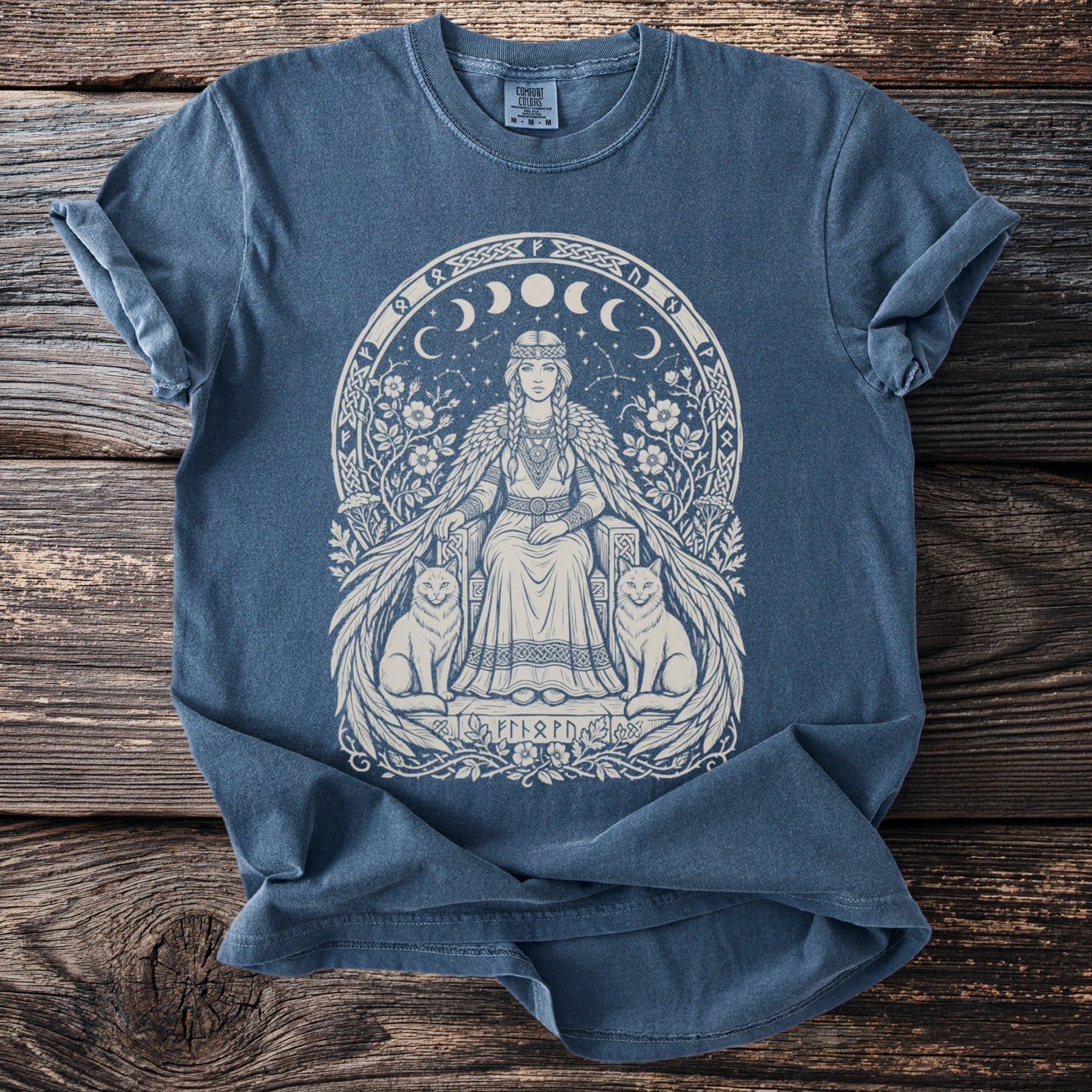 Blue t-shirt with regal woman, cats, moons, and runes graphic design.