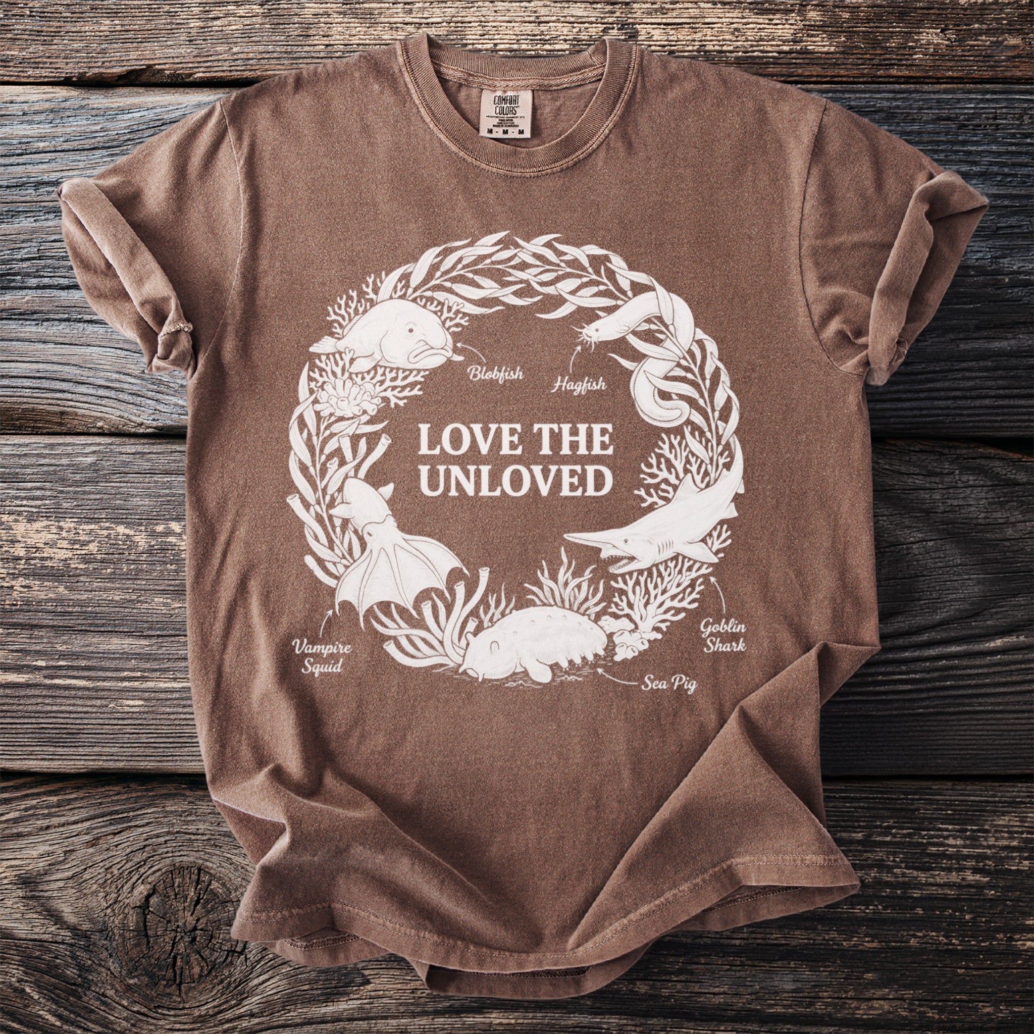 Brown t-shirt with white print of "Love the Unloved" encircled by sea creatures.