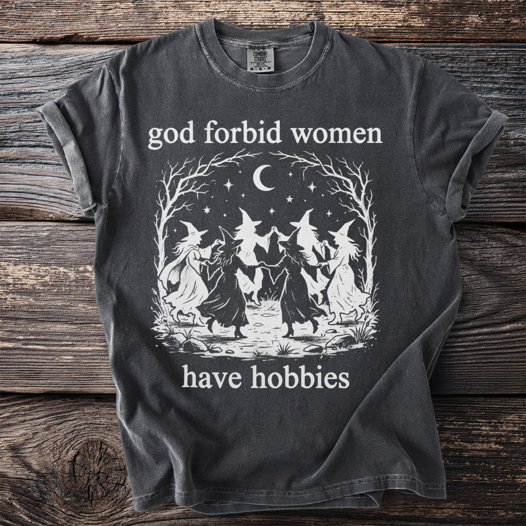 Dark t-shirt with witches dancing and text "god forbid women have hobbies".