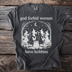 Dark t-shirt with witches dancing and text "god forbid women have hobbies".
