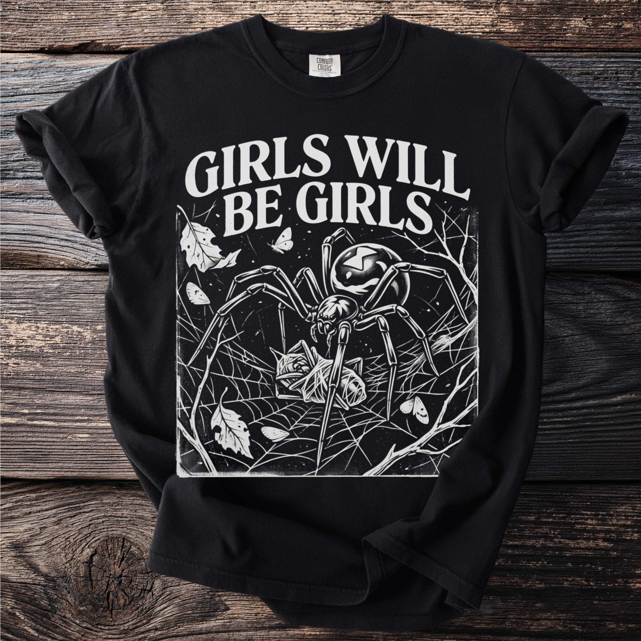 Black t-shirt with white graphic of spider caught prey near "Girls Will Be Girls" text.