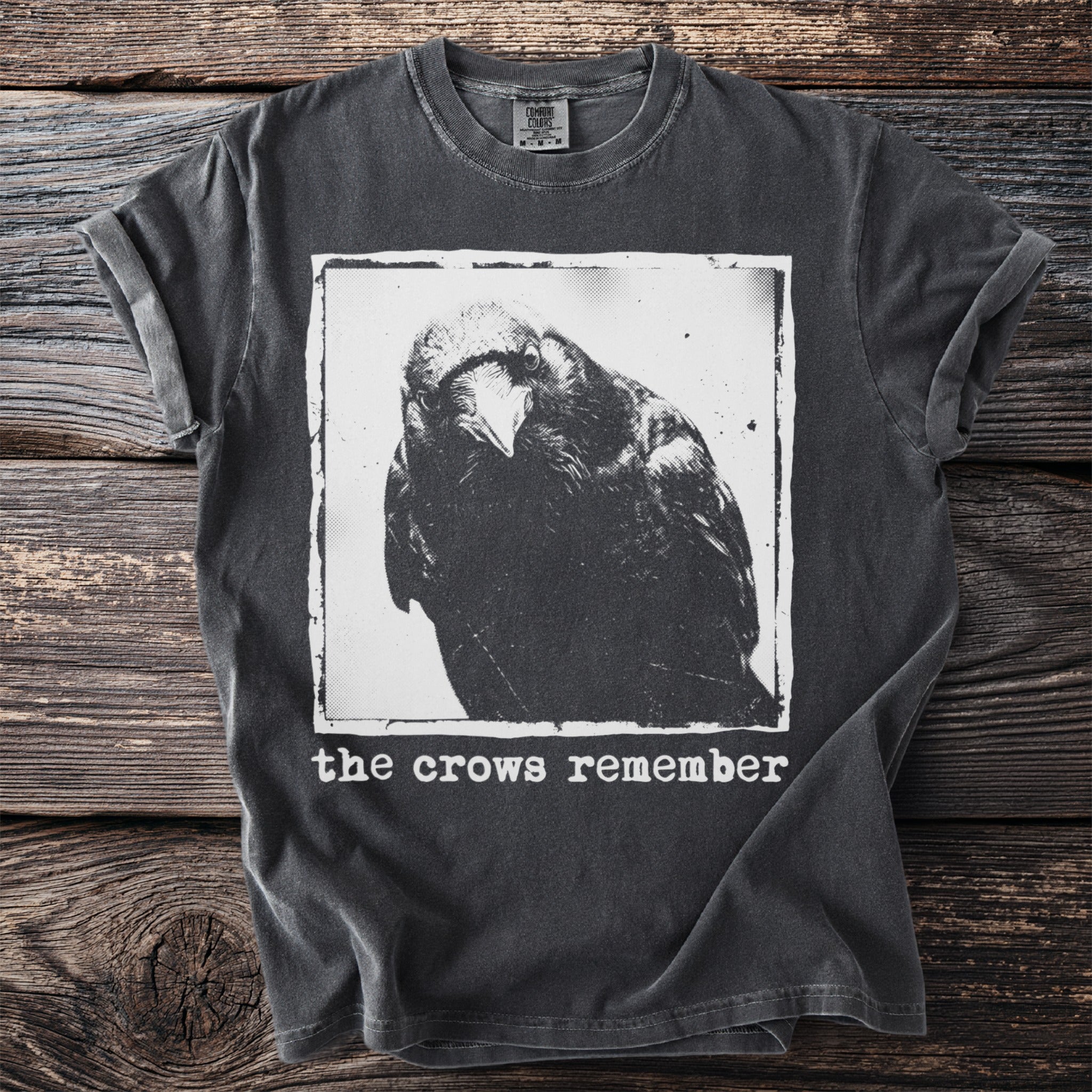 Dark grey t-shirt with a black and white crow graphic and text that reads "the crows remember".