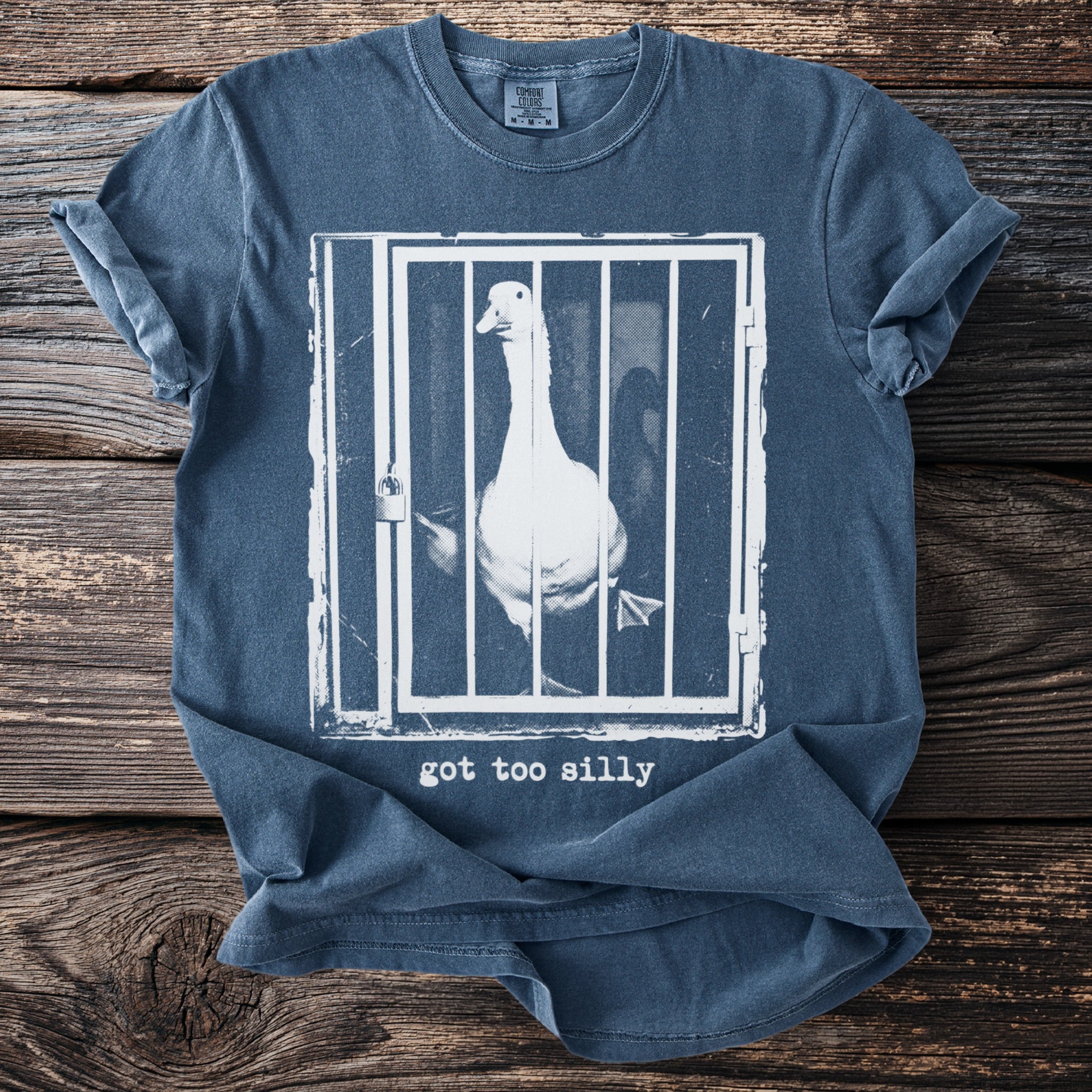 T-shirt with graphic of a goose in a cage and text "got too silly".