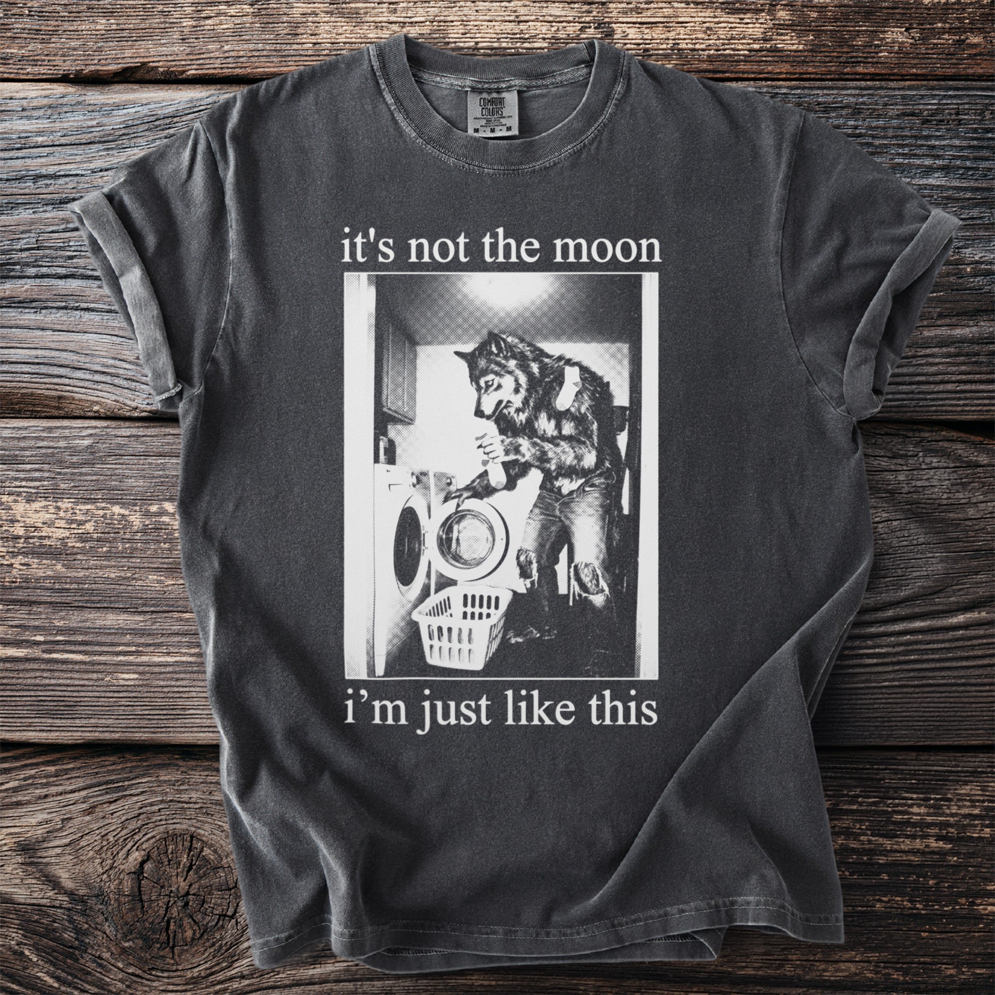 Dark gray t-shirt with graphic of werewolf doing laundry and text "it's not the moon i'm just like this".