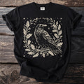 Black t-shirt with a cream raven design surrounded by oak leaves and acorns.