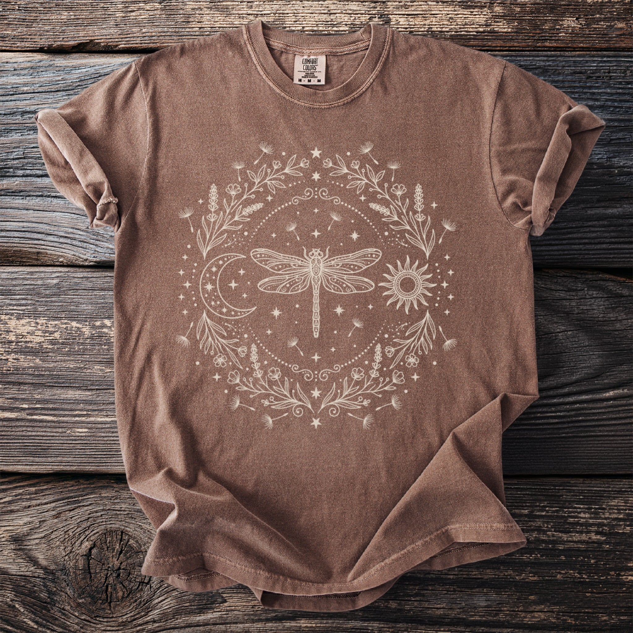Brown t-shirt with cream dragonfly, sun, moon, and floral mandala graphic.
